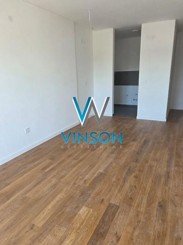 Empty room with wooden flooring and white walls.