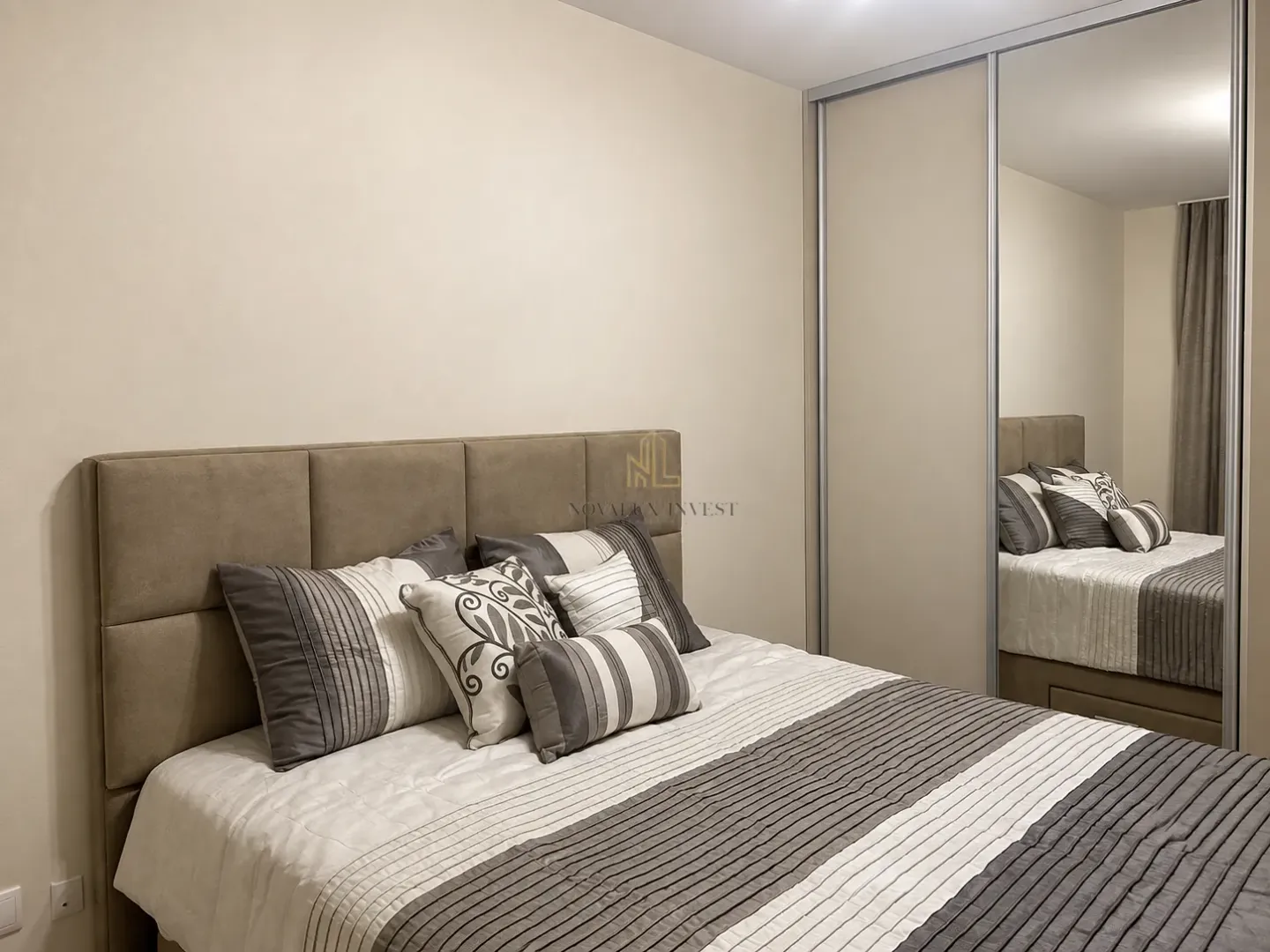 Furnished bedroom with a double bed and a mirrored built-in wardrobe.