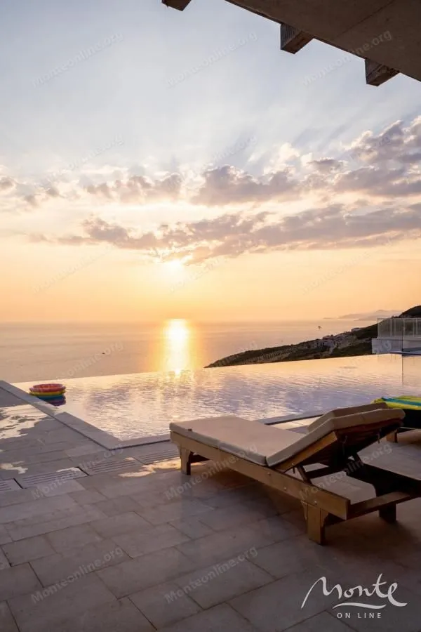 Terrace with a swimming pool and sea view at sunset.
