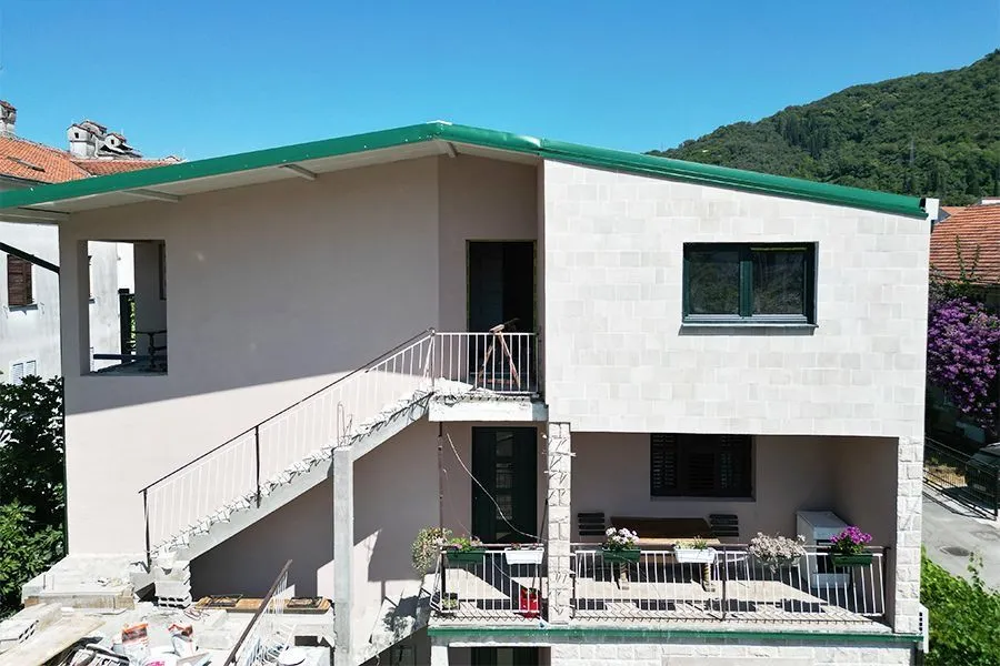 Exterior view of a two-story house with a terrace and an external staircase.