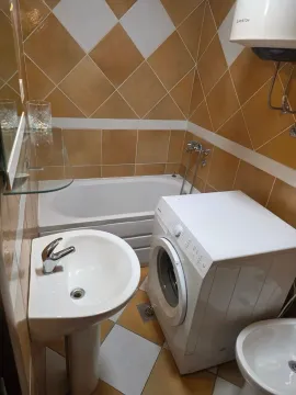 Manje kupatilo obloženo keramičkim pločicama sa kadom, umivaonikom i veš mašinom. - image 11