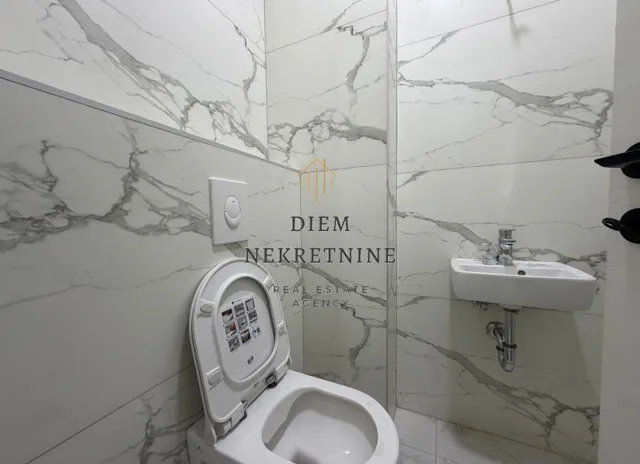 Small bathroom with marble tiles, toilet and washbasin.
