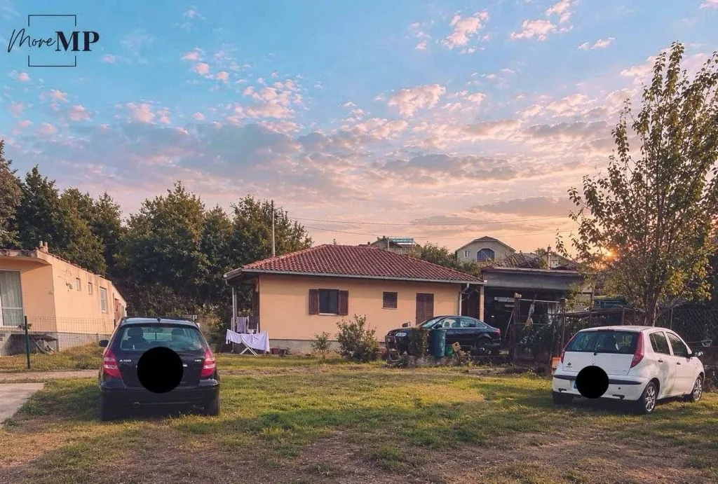 Pogled na dvorište i kuću sa parkiranim automobilima.