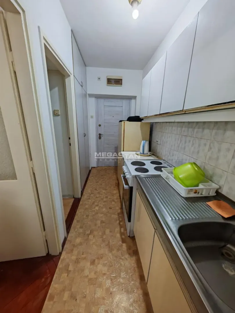 Manja kuhinja sa belim elementima i šporetom.