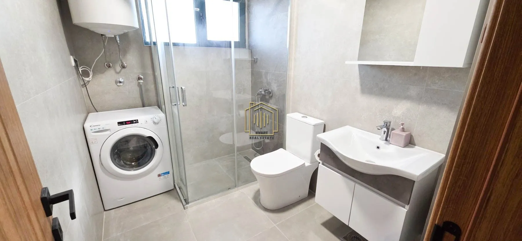 Modernly equipped bathroom with a shower cabin, washbasin, and washing machine.