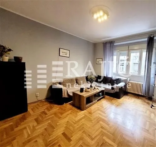 Living room with a seating set, coffee table, and parquet flooring.