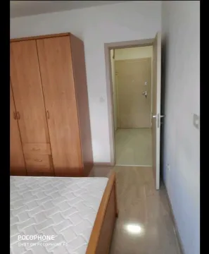 Jednostavna spavaća soba sa drvenim ormarom i krevetom pored otvorenih vrata. - image 6
