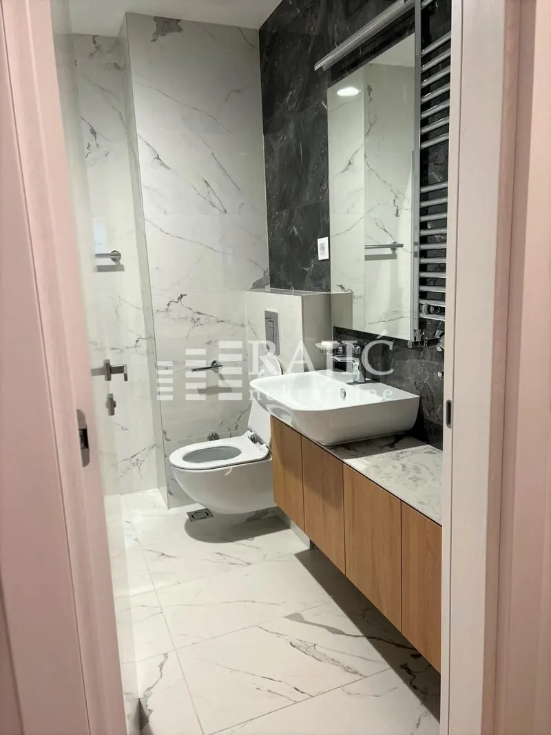 Modern bathroom with a sink, toilet, and marble tiles.