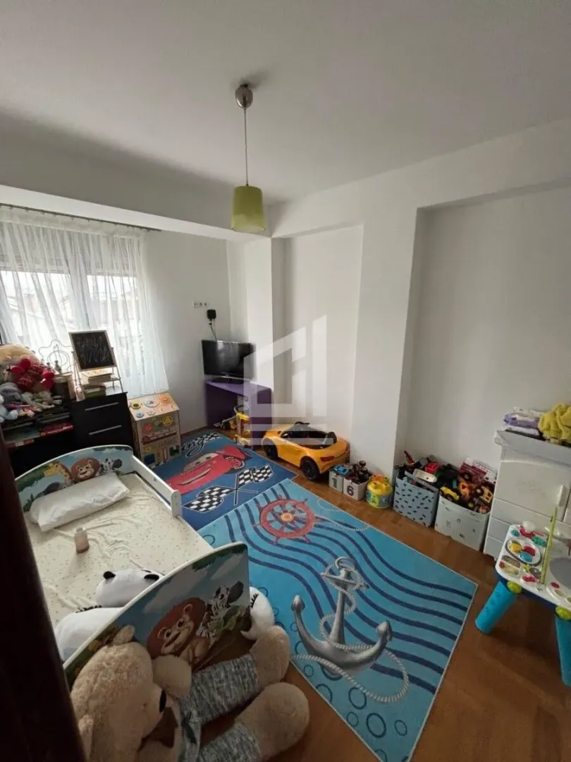 Dječija soba sa krevetom, igračkama i tepihom sa motivima.