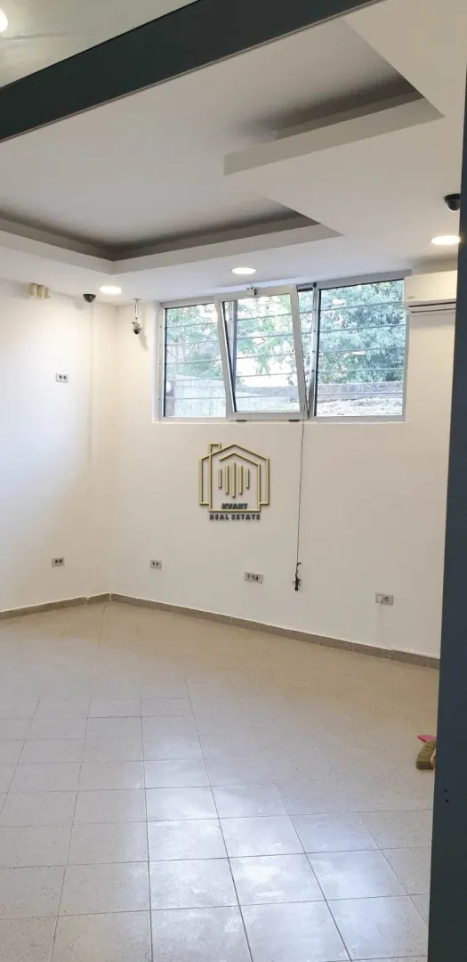 Empty room with white walls, tiled floor, and a window.