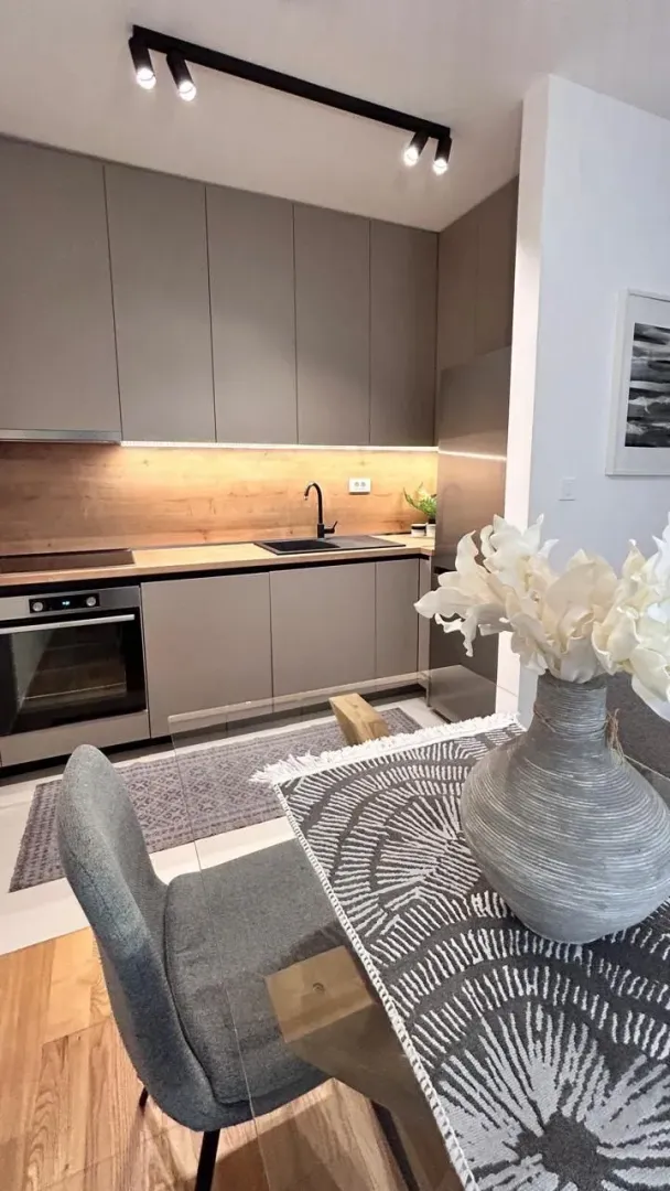 Modern kitchen with grey cabinets and a dining table in the foreground.