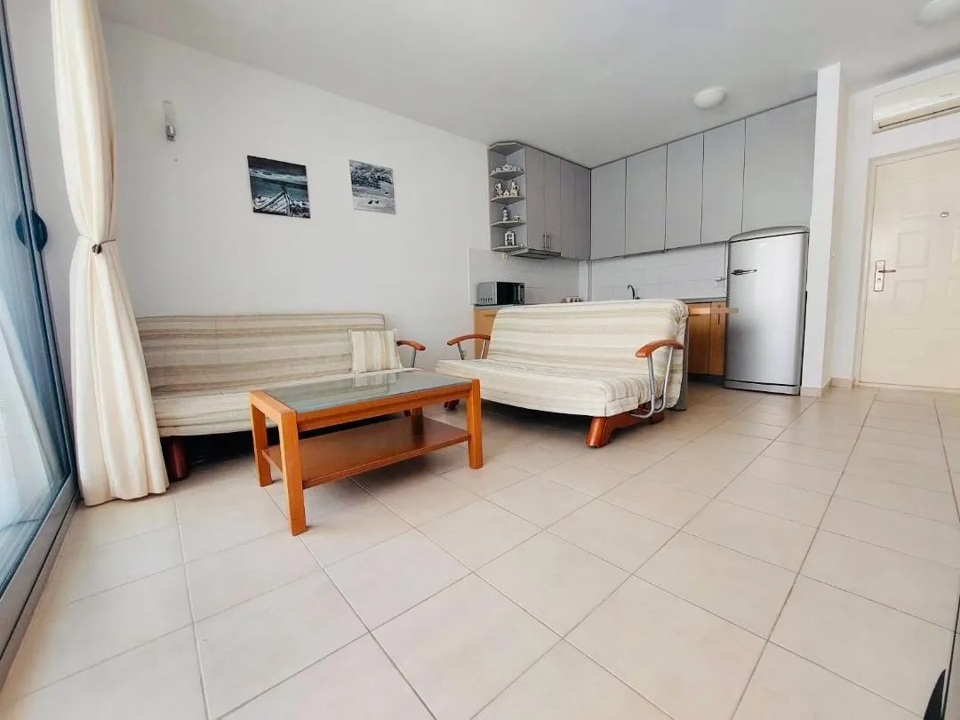 Living room with a seating set and an open-plan kitchen.