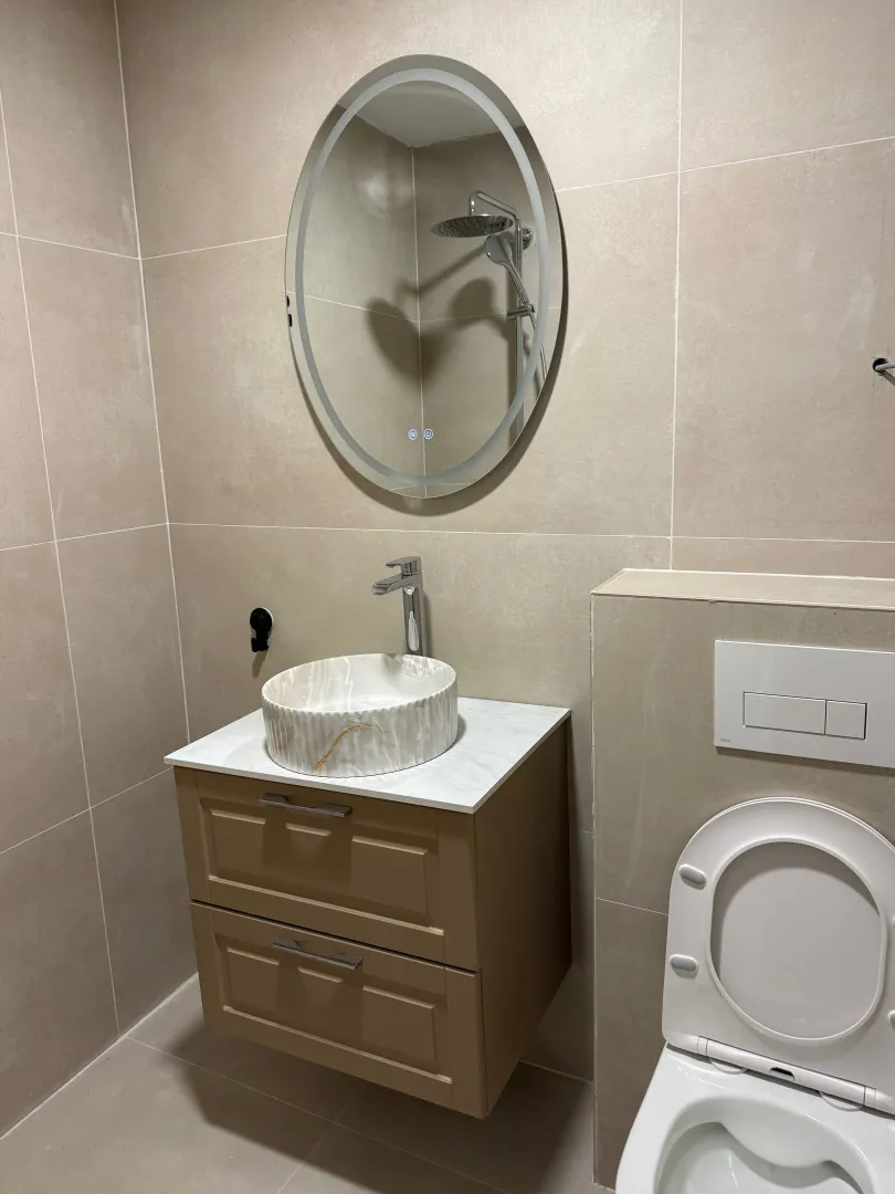 Modern bathroom with a sink, mirror, and toilet.