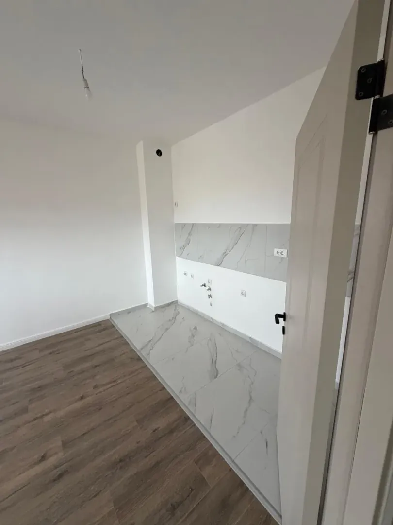 New unfurnished kitchen with ceramic tiles and wooden flooring.