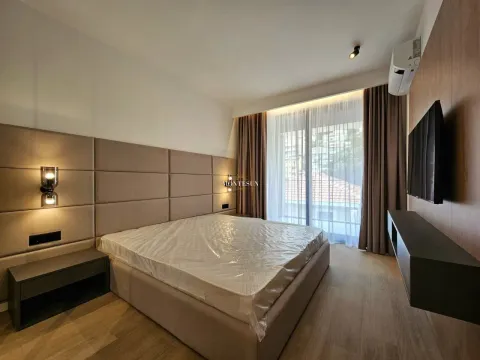 Modern bedroom with a double bed, upholstered headboard, and a wall-mounted TV. - image 4