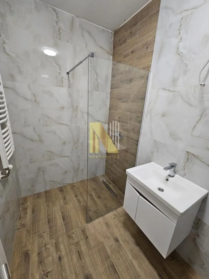 Moderno kupatilo sa tuš kabinom i umivaonikom.