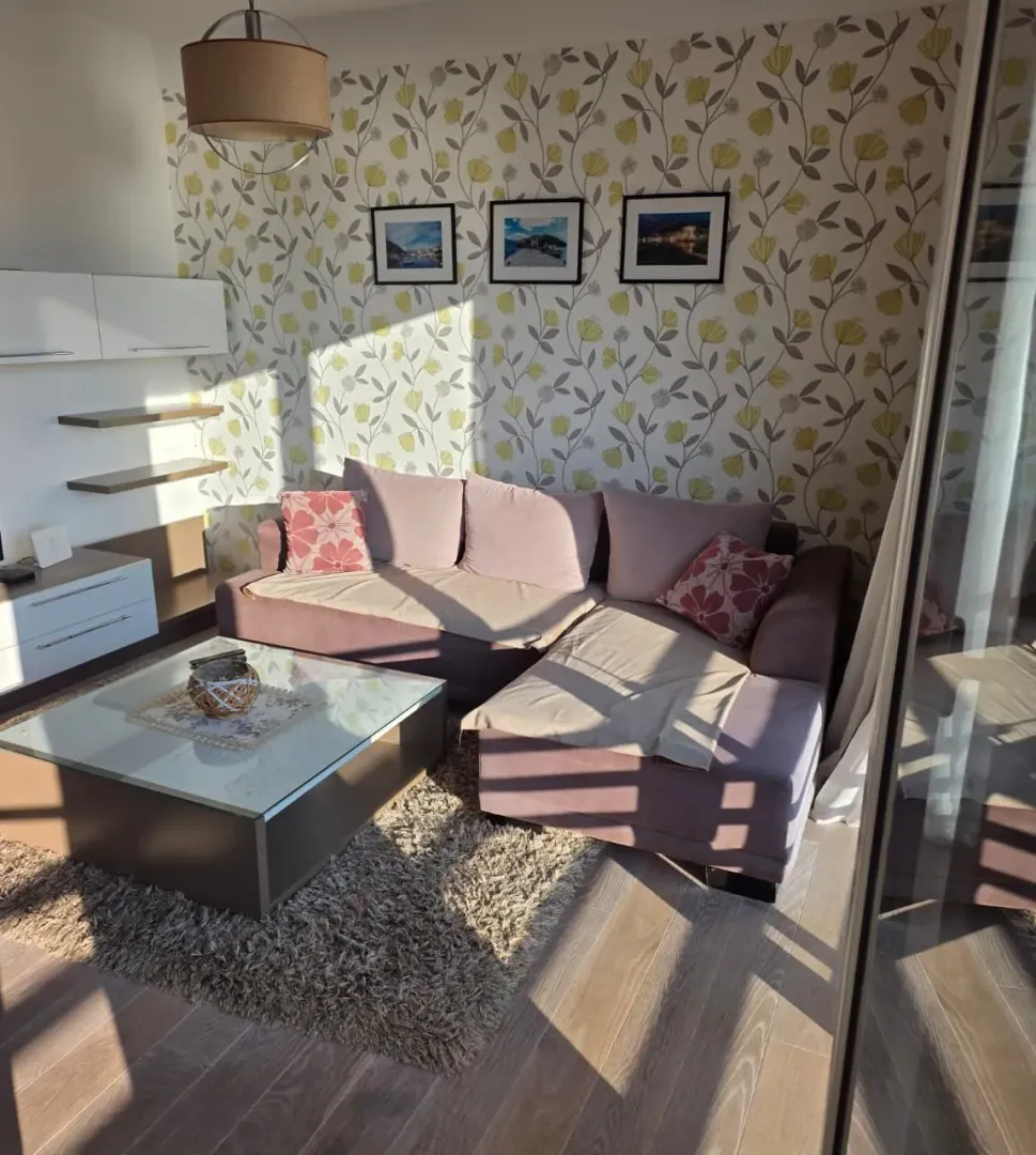 Living room with a sectional sofa, coffee table, and patterned wallpaper.