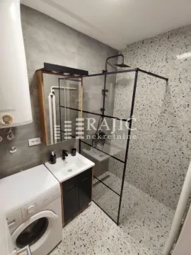 Modern bathroom with a walk-in shower, washbasin, and washing machine. - image 8