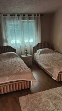 Furnished bedroom with two single beds and white curtains. - image 7