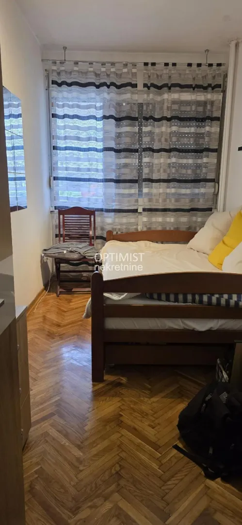 Furnished bedroom with a wooden bed and parquet flooring.