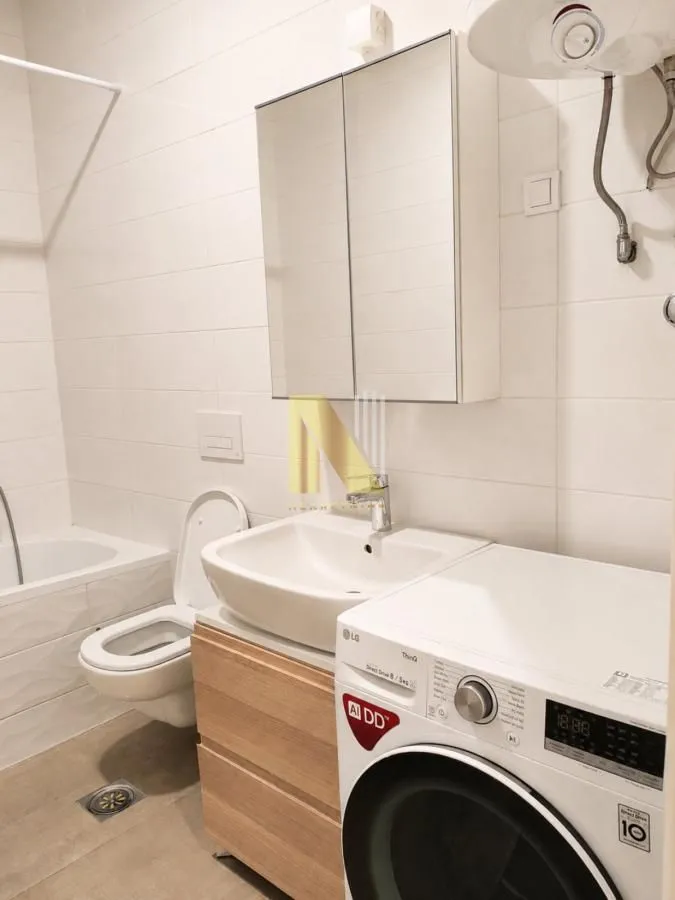 Kompaktno kupatilo sa umivaonikom, WC šoljom, kadom i veš mašinom.