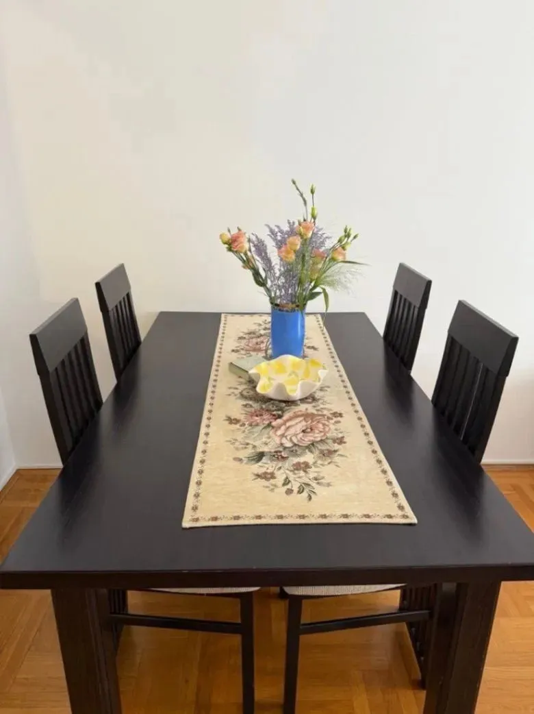 Black dining table with chairs and a vase of flowers.