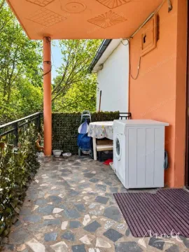 Natkriveni balkon sa mašinom za veš i pogledom na zelenilo. - image 5
