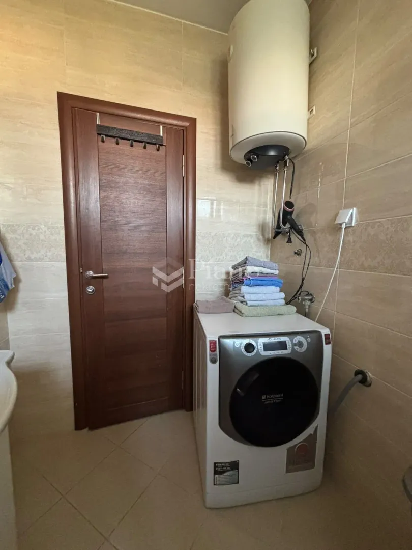 Bathroom with a washing machine, water heater, and a wooden door.