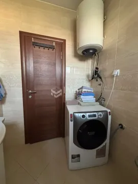 Bathroom with a washing machine, water heater, and a wooden door. - image 10