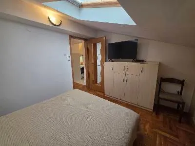 Furnished attic bedroom with a bed, wardrobe, and TV. - image 4