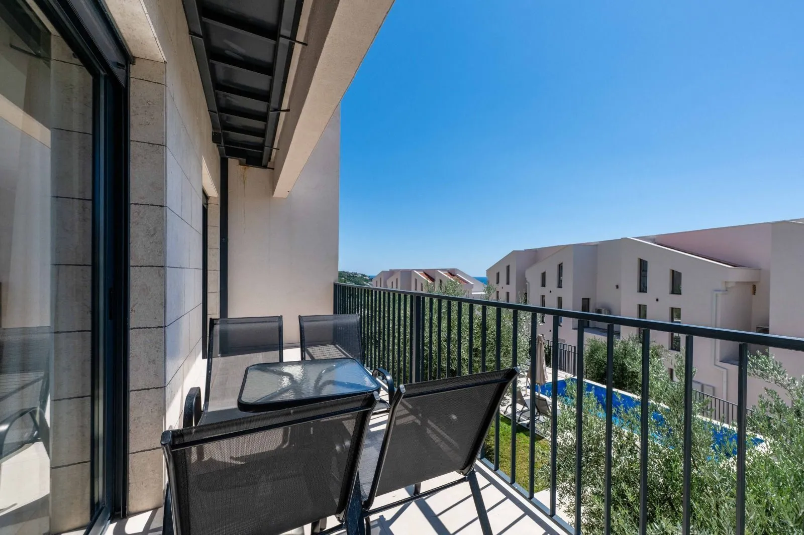 Furnished balcony with seating set and view of surrounding buildings and swimming pool.