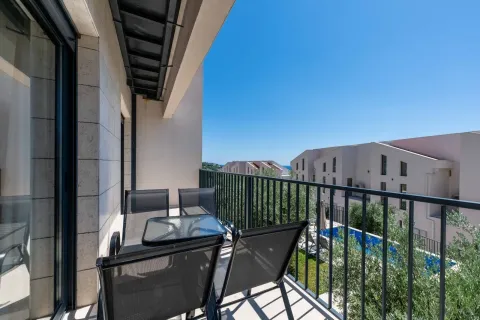Furnished balcony with seating set and view of surrounding buildings and swimming pool. - image 16