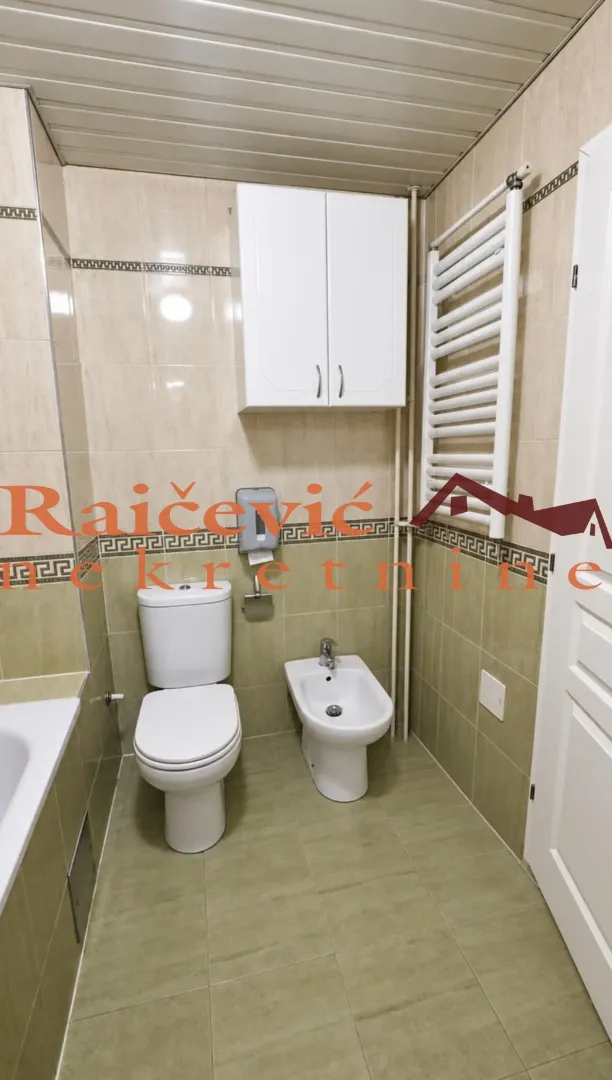 Kompaktno kupatilo sa WC šoljom, bideom, ormarićem i radijatorom.