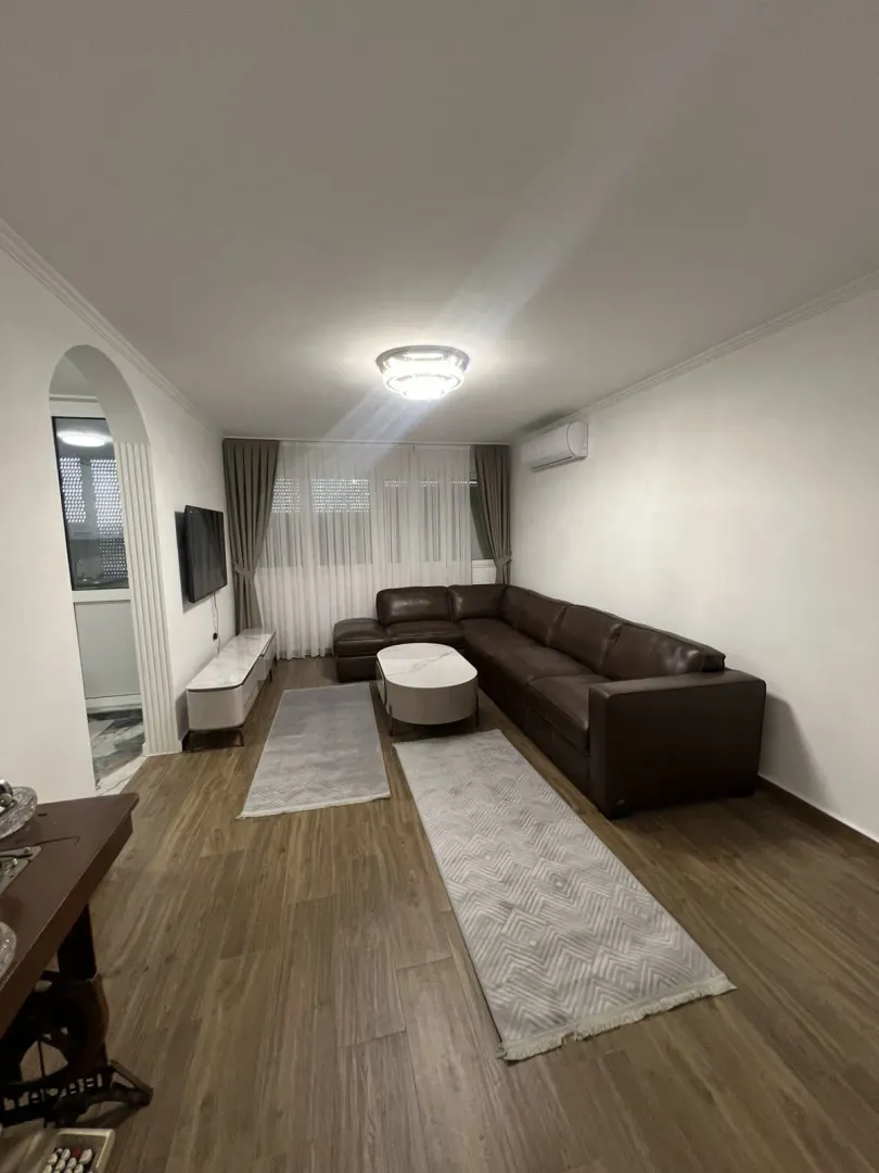 Bright living room with a leather corner sofa and a TV.