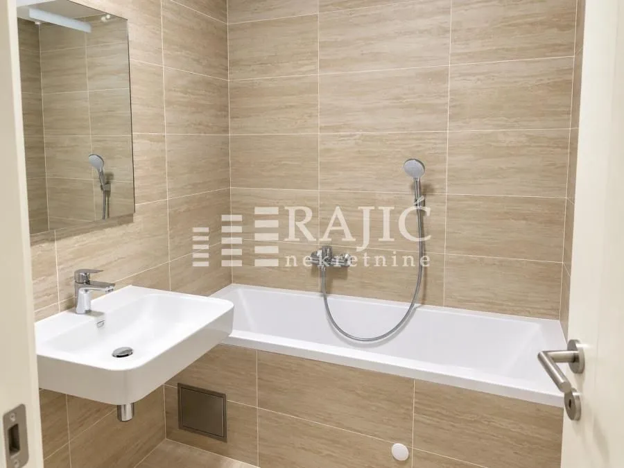 Modern bathroom with a sink and a bathtub tiled with ceramic tiles.