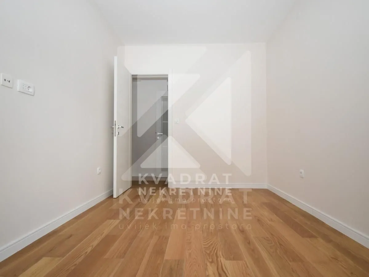 Empty room with hardwood flooring and an open door.