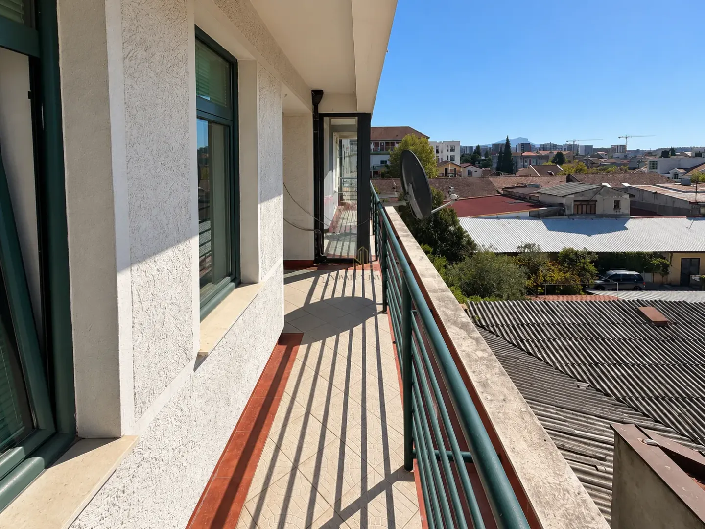 Long tiled balcony with metal railing and a view of the neighborhood.