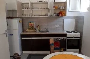 Smaller kitchen with open shelves, refrigerator, and stove. - image 5