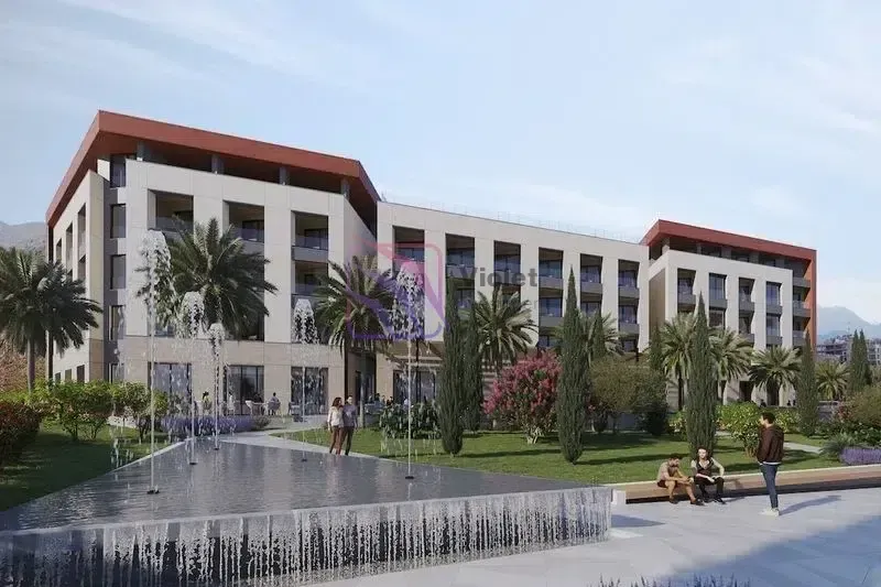 Spoljašnji izgled moderne stambene zgrade sa uređenim dvorištem, fontanom i palmama.
