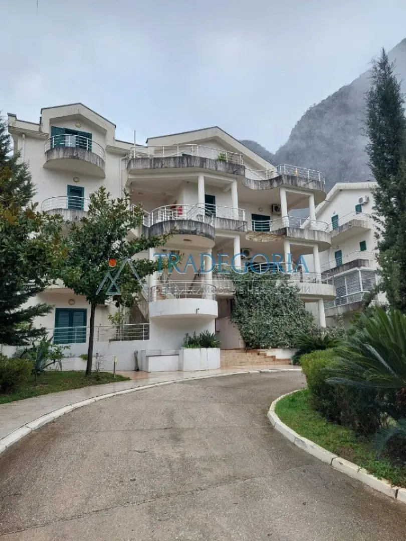 Pogled na spoljašnjost stambene zgrade sa terasama i prilazom.