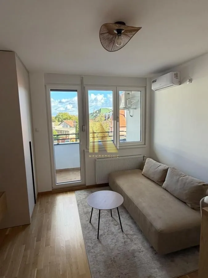 Small living room with a sofa, coffee table, and balcony access.