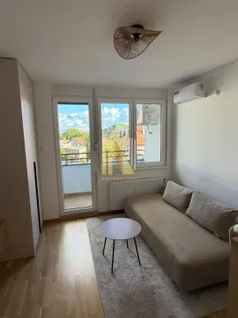 Small living room with a sofa, coffee table, and balcony access. - image 3