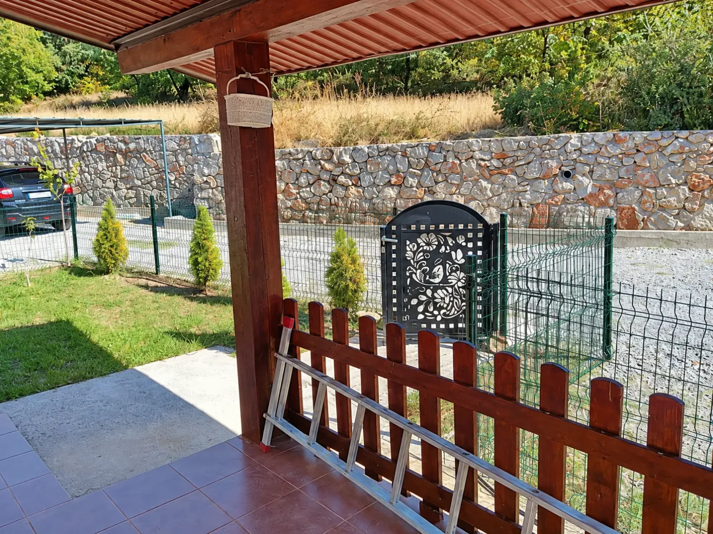 Covered terrace overlooking the yard and stone wall.
