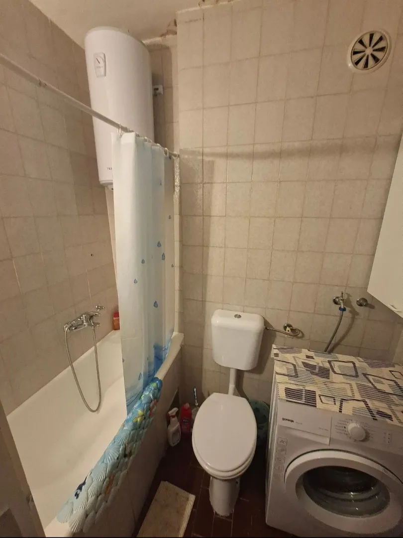 Manje kupatilo sa kadom, toaletom i veš mašinom.