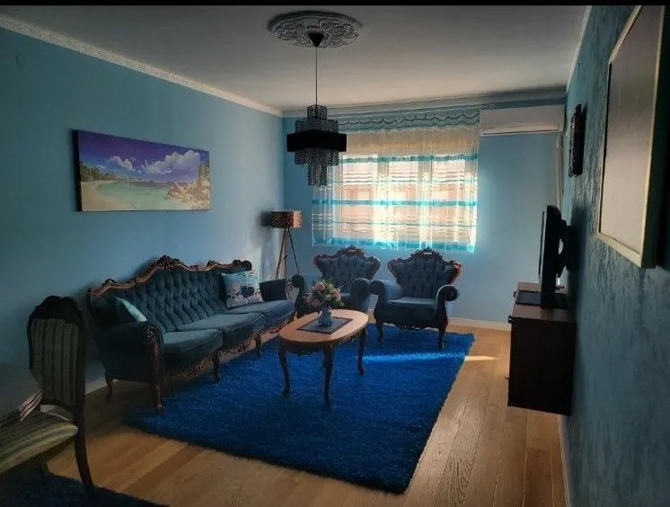 A living room with blue walls, stylish furniture, and a blue rug.