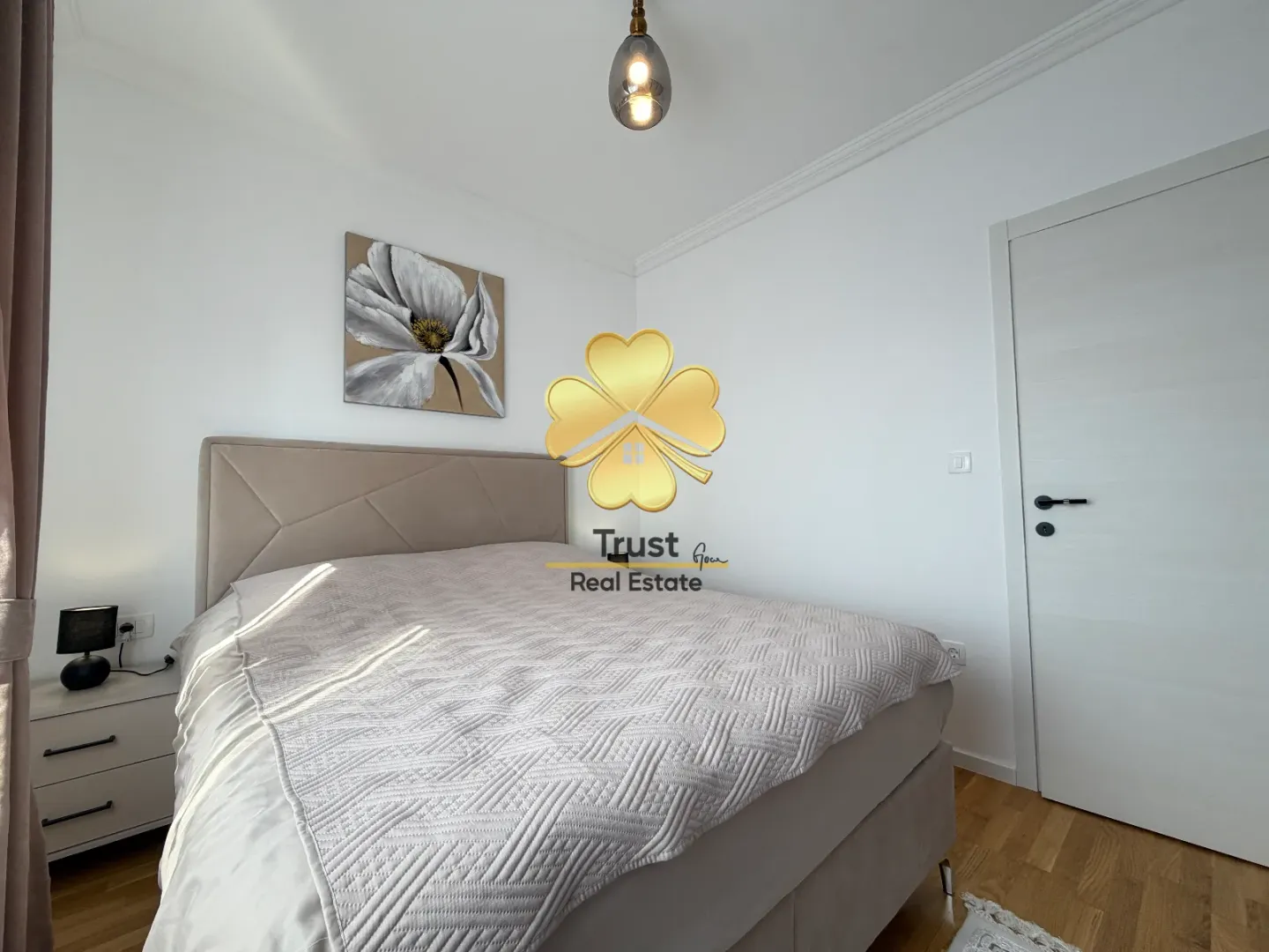 Furnished bedroom with a double bed, nightstand, and a painting on the wall.