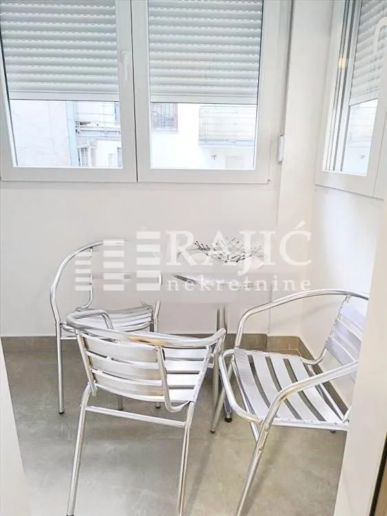 Enclosed terrace with a table and metal chairs.