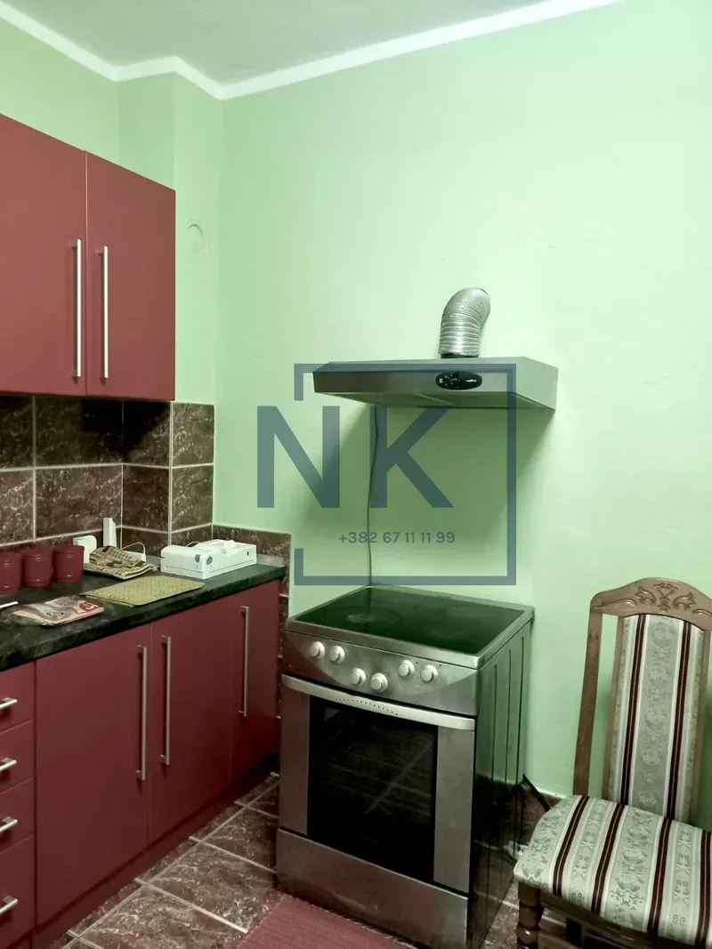 Smaller kitchen with red cabinets, a stove, and an extractor hood.