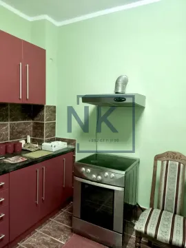 Smaller kitchen with red cabinets, a stove, and an extractor hood. - image 3