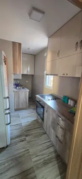 Small kitchen with wooden cabinetry and built-in appliances. - image 3